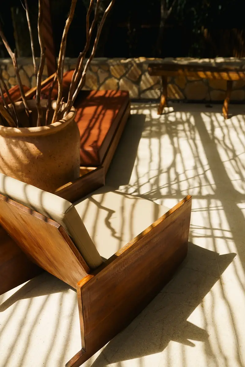 Poltronas de madeira com a sombra das árvores