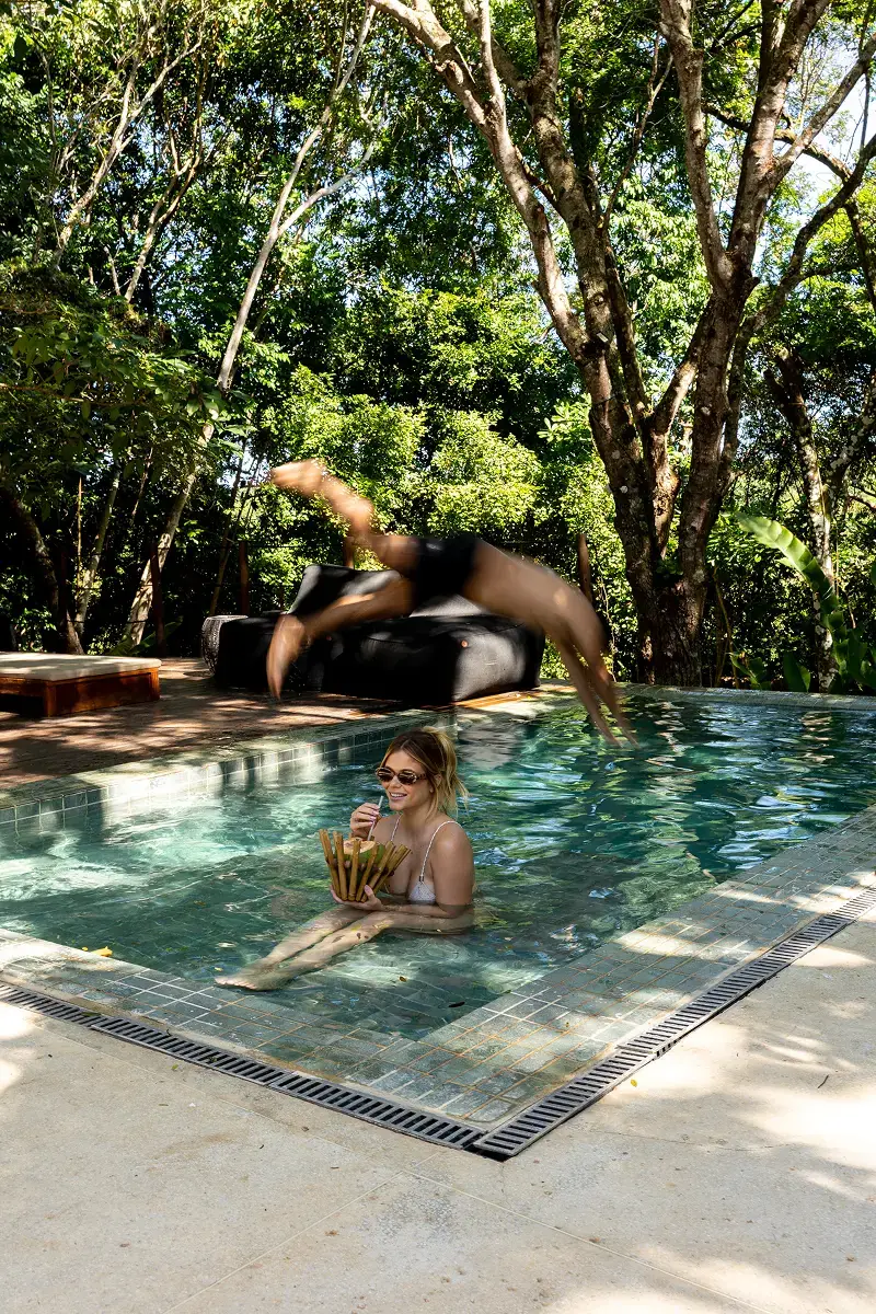 Hóspede na piscina da pousada, entre as árvores