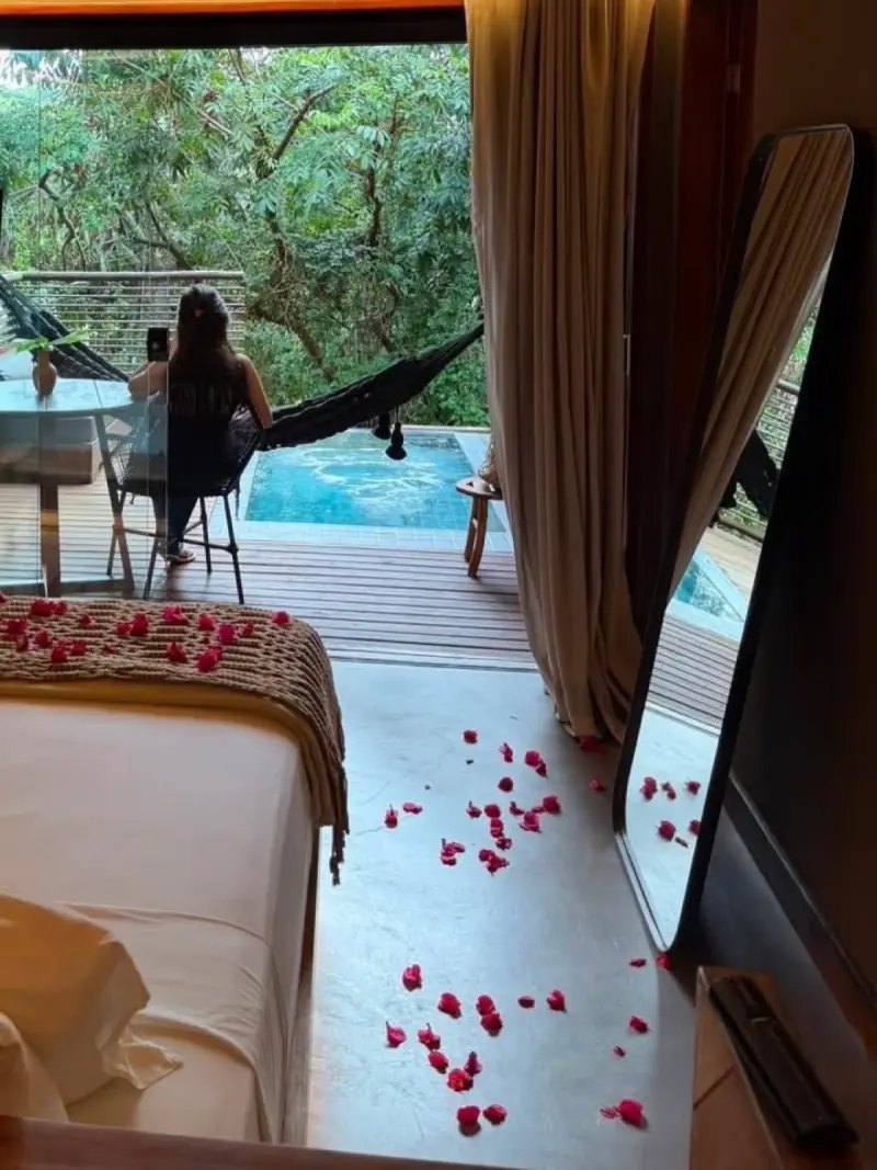 Quarto com pétalas de rosa no chão e a piscina ao fundo